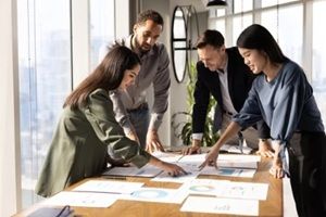 multiethnic team of analysts working on paper sales reports