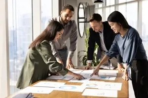 multiethnic team of analysts working on paper sales reports